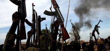 Rebel fighters hold up their rifles as they walk in front of a bushfire in a rebel-controlled territory in Upper Nile State, South Sudan February 13, 2014. [Photo: REUTERS/Goran Tomasevic]