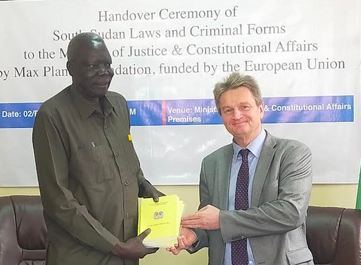 Justice Minister Ruben Madol Arol (L) received the printed laws from EU Ambassador Timo Olkkonen (R). (Photo:Radio Tamazuj)